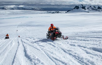 Een sneeuwscooterrijder zoeft over een ijskap in IJsland.