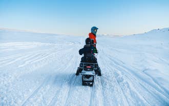 A rider speeds across snowy terrain during a Langjokull snowmobile tour.
