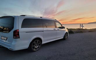 White luxury van parked on a road in Iceland during sunset with colorful skies in the background.