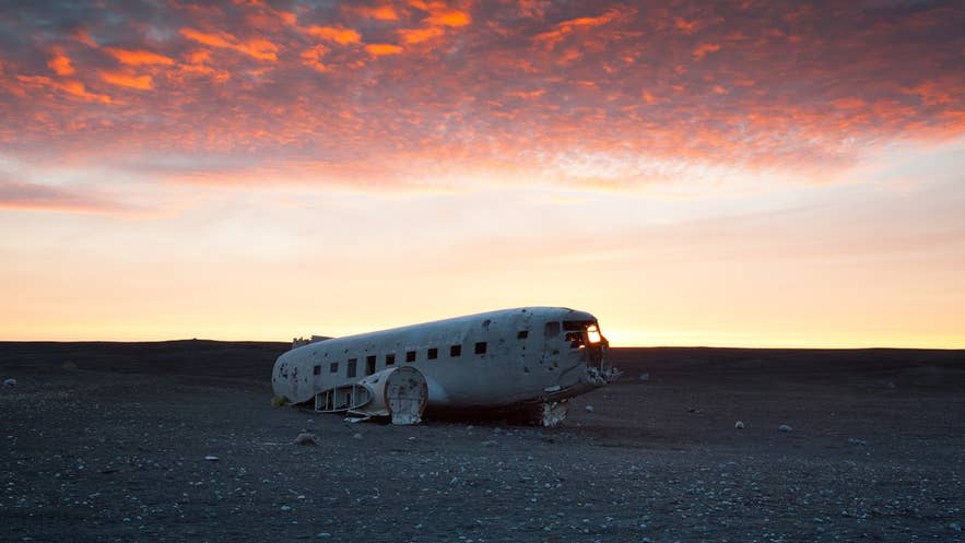 Het DC3 vliegtuigwrak vormt een opvallend contrast met de kale omgeving