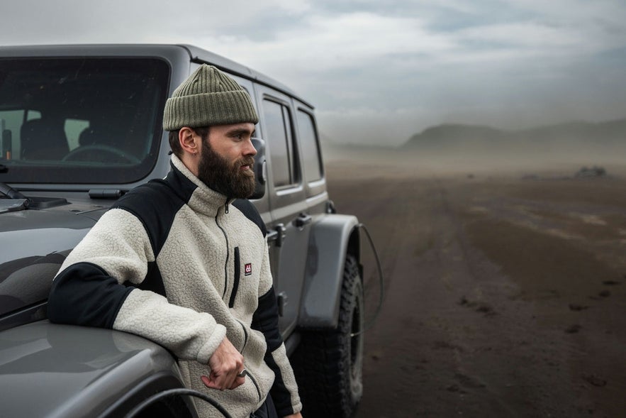 Traveler in 66&deg;North clothing standing by a jeep in Iceland&rsquo;s rugged terrain