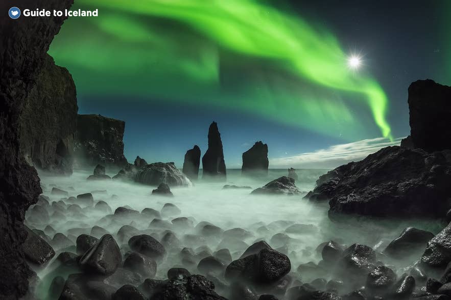 Aurore boreali sul Reykjanes, sopra una costa rocciosa avvolta dalla foschia marina e spettacolari faraglioni di basalto, di notte