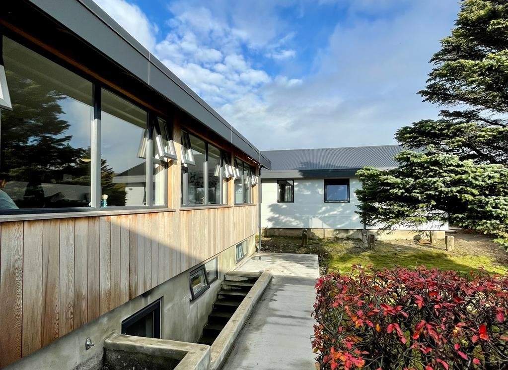 Front hostelu Hofn HI z kwiatami na zewnątrz.