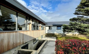 Фасад хостела Hofn HI Hostel с цветами у входа.