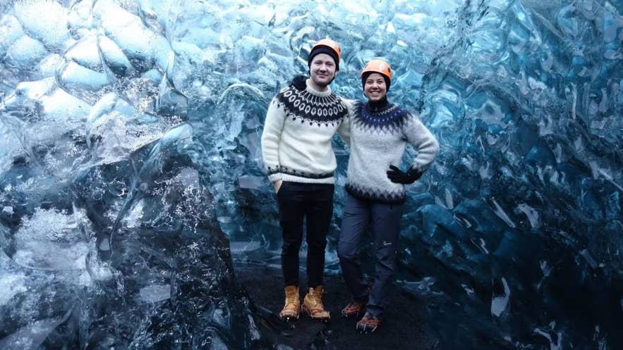 Пара в свитерах лопапейса в ледяной пещере, тепло одеты для зимнего тура по Исландии.