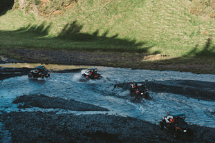 An aerial view of four buggies driving through a river on the Myrdalsjokull glacier.