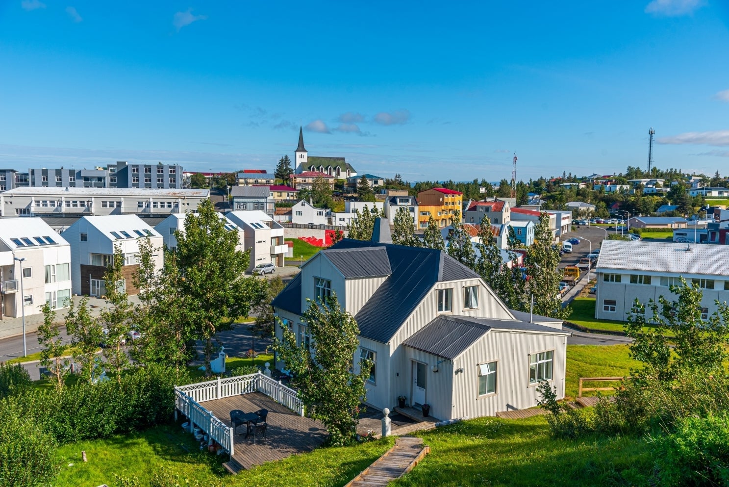 ภาพมุมสูงของบอร์การ์เนส ประเทศไอซ์แลนด์ บ้านสีขาว พื้นที่สีเขียว บ้านหลากสี และยอดโบสถ์ใต้ท้องฟ้าสีฟ้าใส