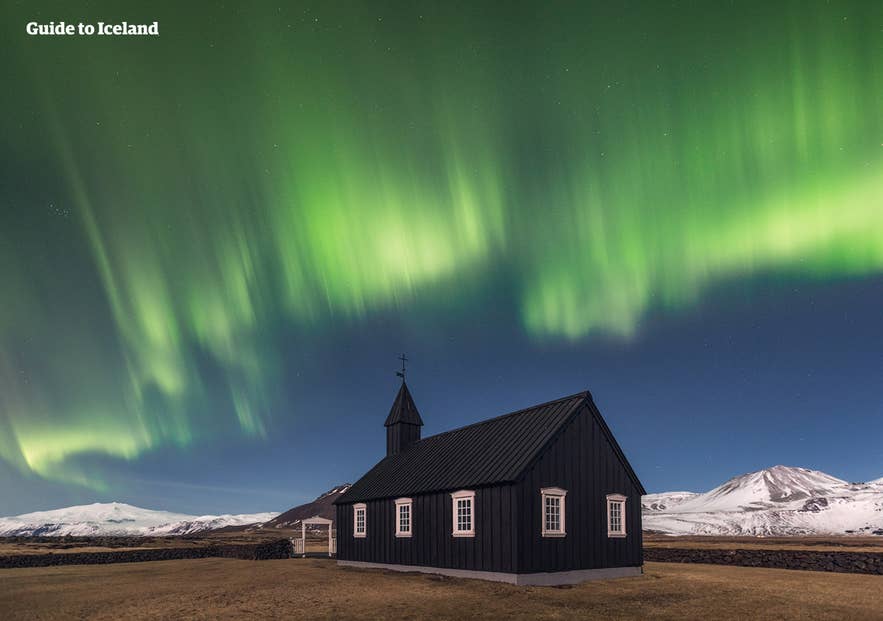Northern lights dancing above the Búðakirkja black church on the Snæfellsnes Peninsula in Iceland.