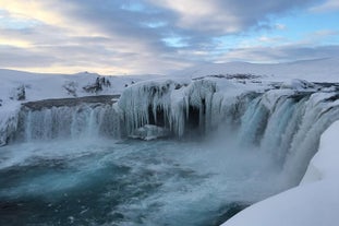 A frosty wonderland surrounds the majestic Godafoss during the winter months.