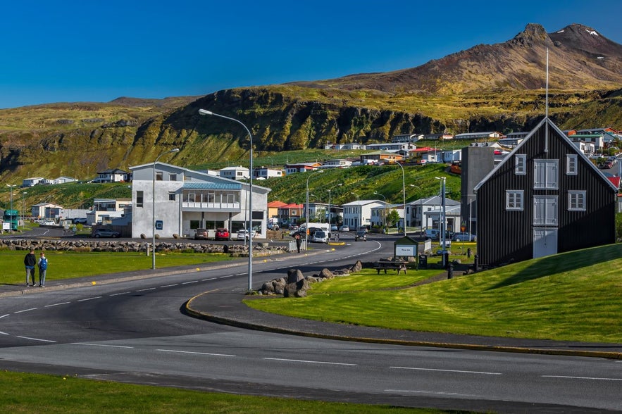 Sunny day in Ólafsvík, a coastal town on Iceland’s Snæfellsnes Peninsula, with colorful houses beneath green hills and mountains.