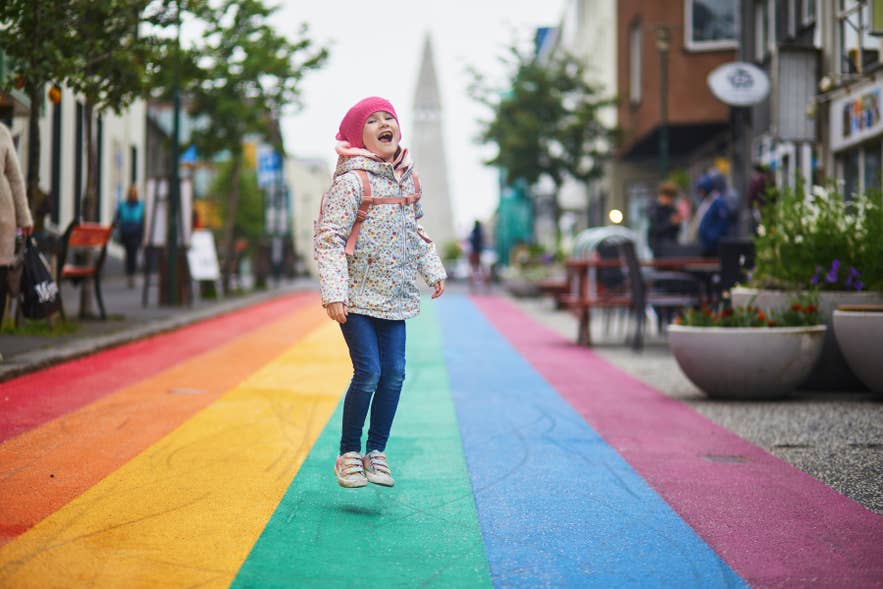 Happy adorable preschooler girl having fun on a rainbow street Lugavegur in Reykjavik, Iceland, in spring. Happy adorable preschooler girl having fun on a rainbow street Lugavegur in Reykjavik, Iceland, in spring.