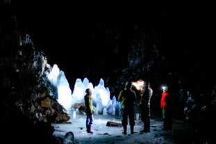 People standing, surrounded by ancient ice formations, some over 400 years old, at Lofthellir ice cave.