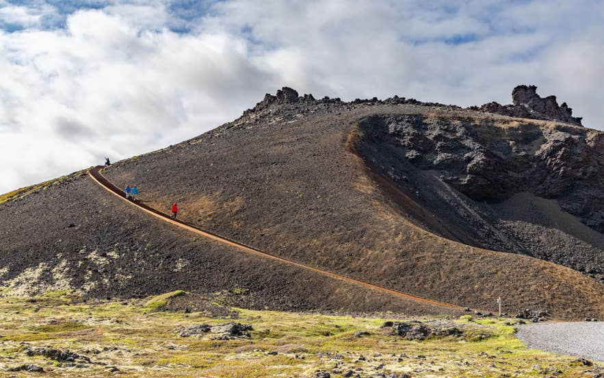Travelers hiking up the Saxholl Volcanic Crater with a clear path leading to the summit on the Snaefellsnes Peninsula.
