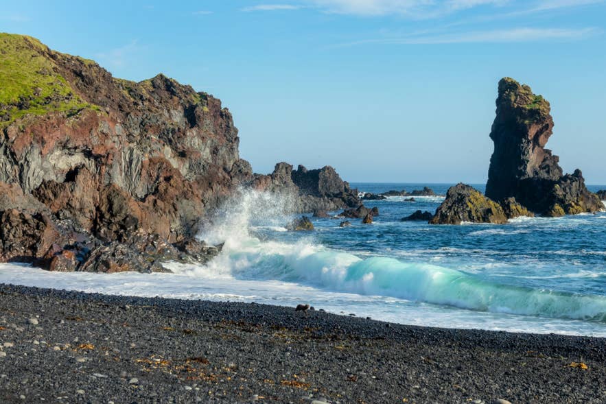 Waves crashing against rugged lava cliffs at Djupalonssandur Black Sand Beach on the Snaefellsnes Peninsula.