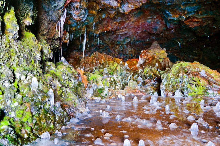 Colorful rock formations and natural ice stalagmites inside Vatnshellir Lava Cave on the Snaefellsnes Peninsula.
