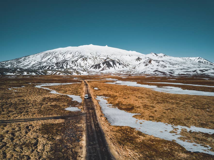 Snow-covered Snaefellsjokull Glacier rising above a remote mountain road on the Snaefellsnes Peninsula.