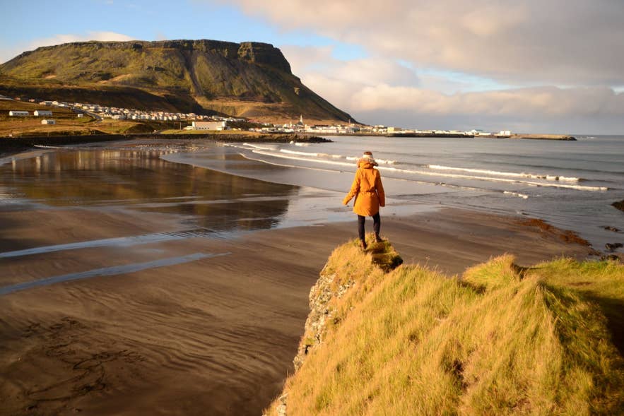 Traveler overlooking the sandy coastline and mountains near Olafsvik on the Snaefellsnes Peninsula.