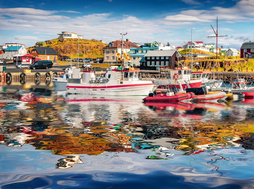 Fischerboote spiegeln sich im bunten Wasser des Hafens von Stykkisholmur auf der Snaefellsnes-Halbinsel.