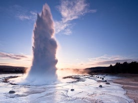The Strokkur geyser erupts as the sun starts to set.