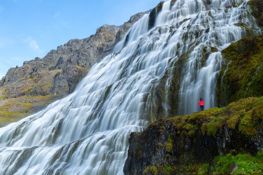 Person standing in front of the magnificent Dynjandi Waterfall at the Westfjords, Iceland