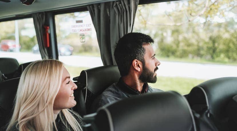 A smiling couple looks out the window of a tour vehicle during a multi-day trip in Iceland.