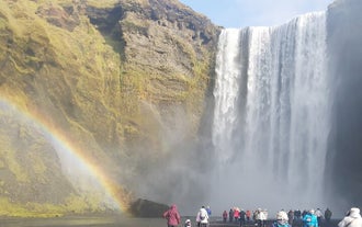 As sunlight filters through the spray, a vivid rainbow emerges, adding a touch of magic to the already enchanting Skogafoss.