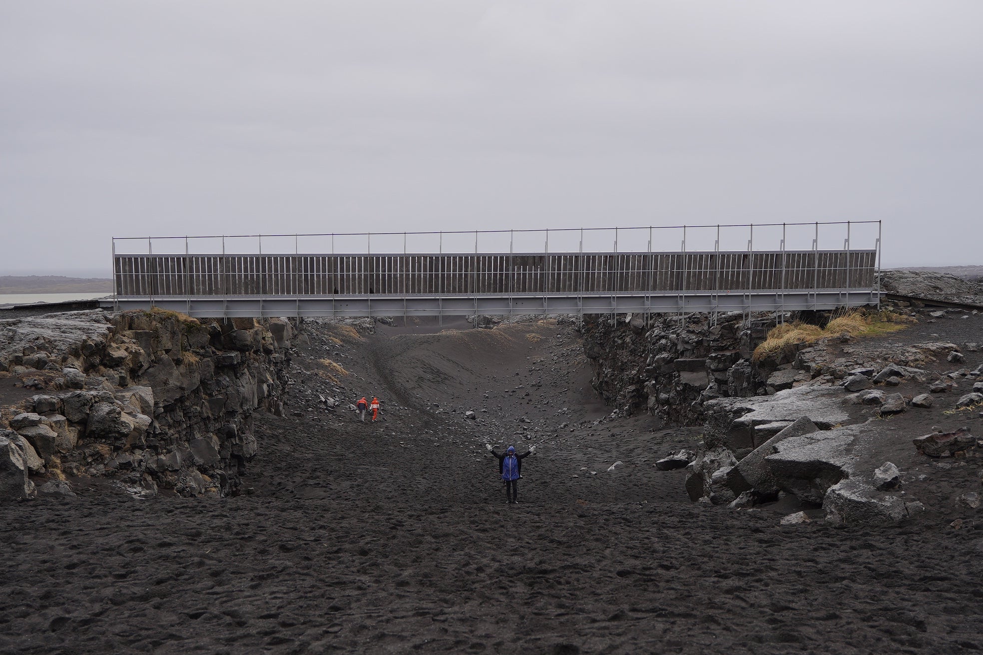 People walk under the Bridge Between Continents in the Mid-Atlantic rift on the Reykjanes Peninsula.
