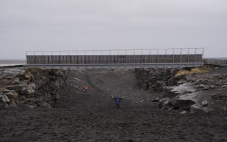 People walk under the Bridge Between Continents in the Mid-Atlantic rift on the Reykjanes Peninsula.