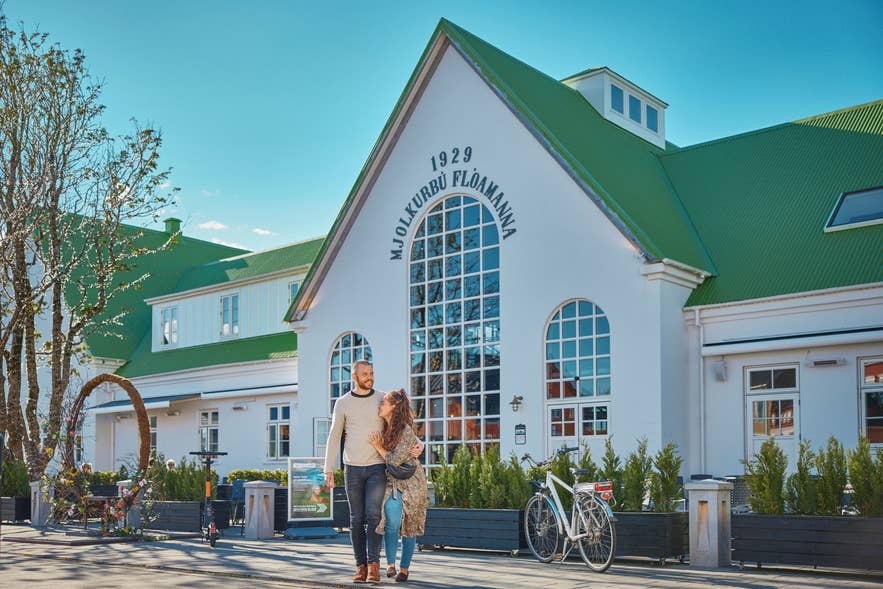 Ein Paar spaziert vor der Mjolkurbud Floamanna im New-Old-Town-Viertel von Selfoss, einem historischen Wahrzeichen im Süden Islands.