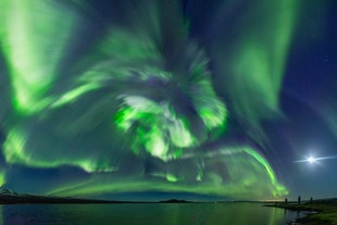 A swirl of northern lights appears on a coastal area near Reykjavik.