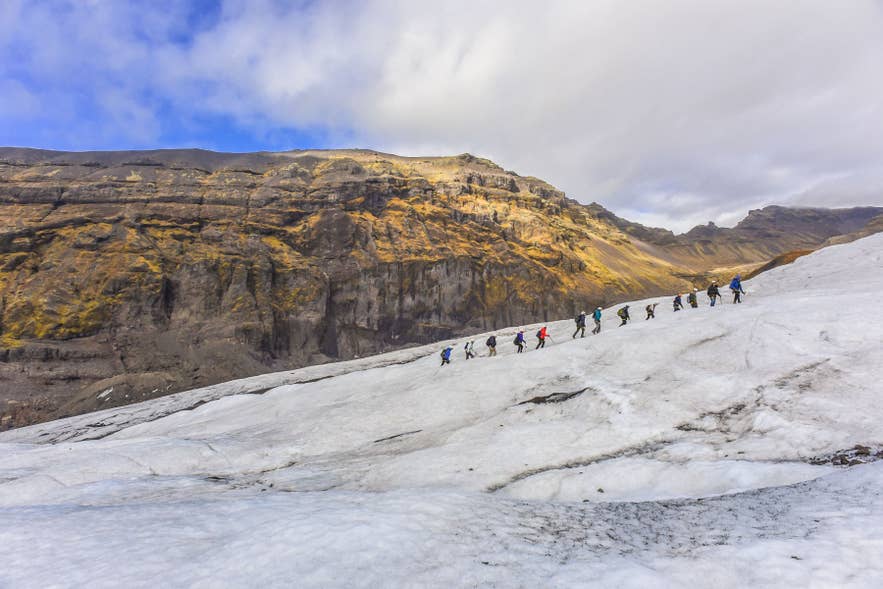 アイスランドの氷河ハイキングツアーで、ガイドに率いられた登山者のグループが氷河を歩いている。