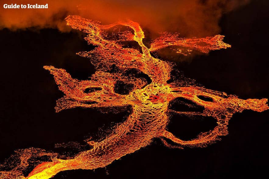 Aerial view of glowing lava flowing across the landscape during a volcanic eruption in Iceland.