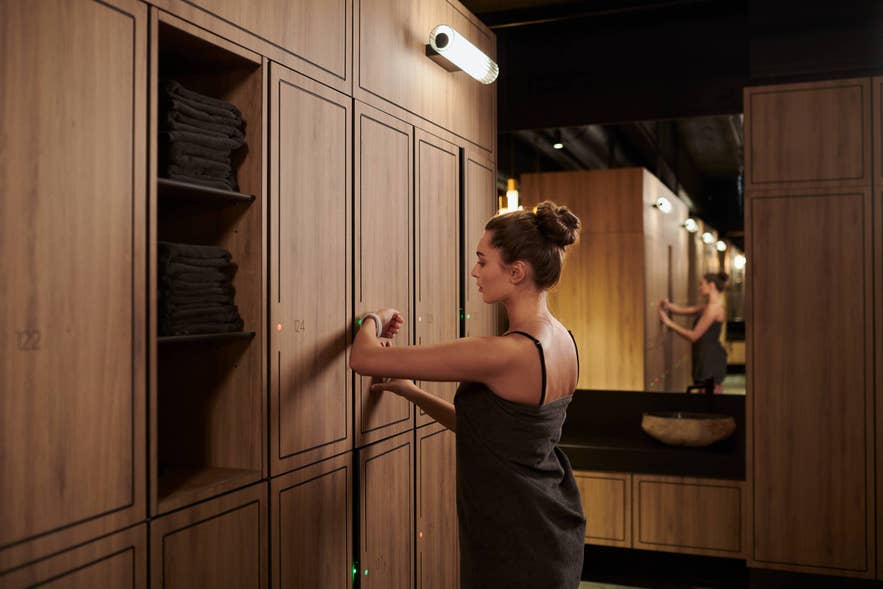 アイスランドのスパ更衣室で、温泉プールに入る前にシャワーの準備をする女性。