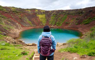 Traveler overlooking Kerid Crater’s turquoise lake and red slopes on a Golden Circle tour.