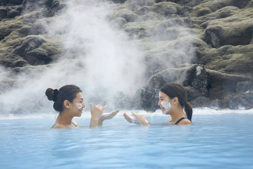 Due visitatori si rilassano nella Laguna Blu, la spa geotermica più famosa d’Islanda, durante l’alta stagione di agosto.