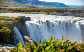 Water rushes down a cliff at Godafoss Waterfall in North Iceland in summer.