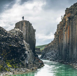 A person stands atop Studlagil canyon, renowned for its mesmerizing basalt column formations.