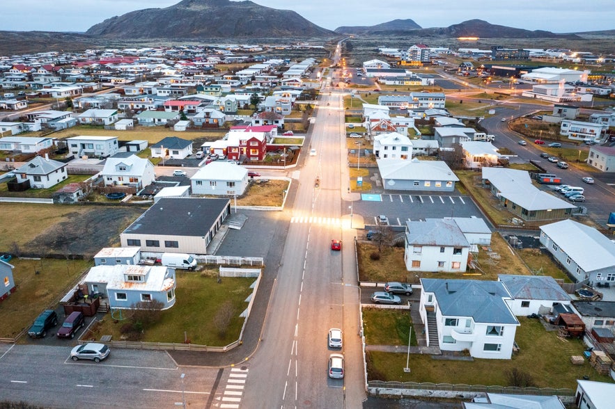Aerial view of central Grindavik, Iceland, with Reykjanes mountains and houses along Víkurbraut Street at dusk.