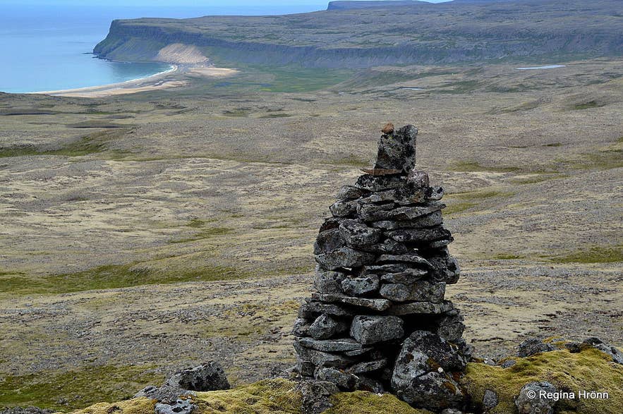 Traditionelles isländisches Steinmännchen (Varða), das als Wegweiser dient, mit Blick auf die Küste der Westfjorde.