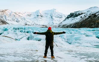 Wanderer wandert auf dem Vatnajökull-Gletscher mit blauem Eis und schneebedeckten Bergen in Island.