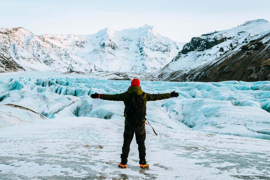 Vandrare som går på Vatnajökull-glaciären med blå is och snötäckta berg på Island.