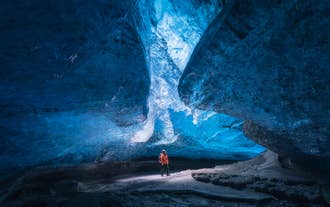 Reiziger in een blauwe ijsgrot op de Vatnajökull-gletsjer tijdens een begeleide ijsgrottentocht in IJsland.