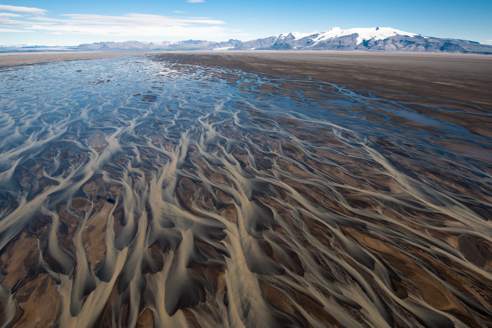 Take in the vast network of braided rivers below, an intricate web that winds its way through Iceland's captivating landscapes.