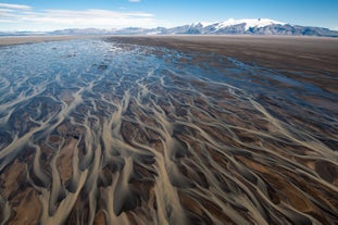 Take in the vast network of braided rivers below, an intricate web that winds its way through Iceland's captivating landscapes.