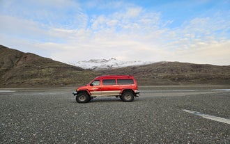 A red super jeep parked in front of snowy mountains.