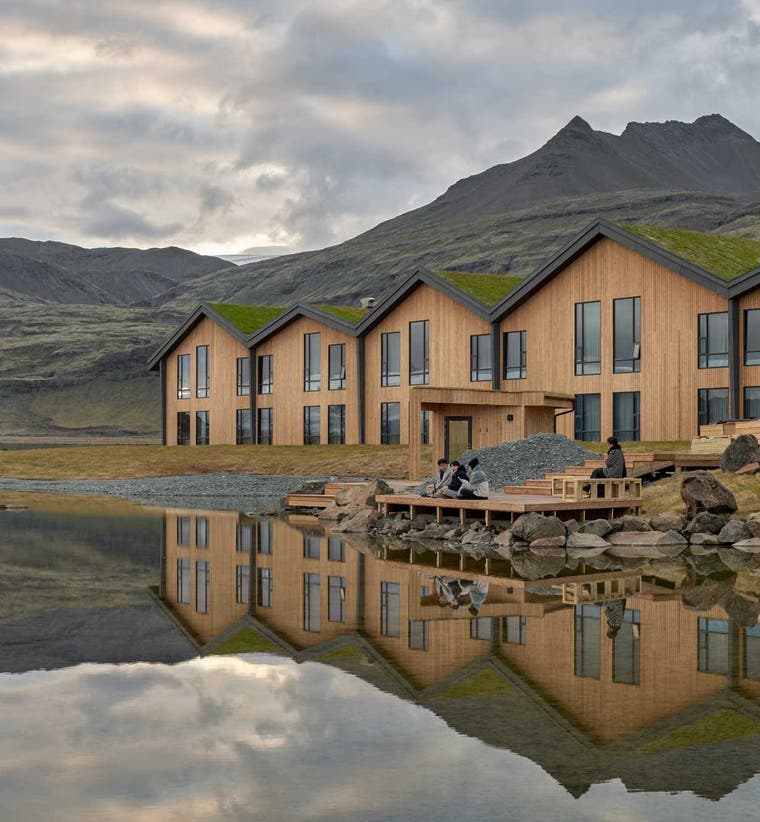 Modern 4-star hotel in Iceland by a lake with wooden design, mountain views, and clear reflections.