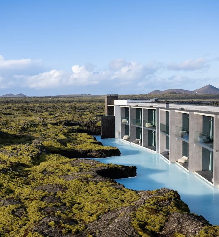 Luxury hotel in Iceland with a private lagoon, set in a volcanic lava landscape under a clear sky.