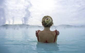 A woman enjoying a soak in the milky blue waters of the Blue Lagoon.
