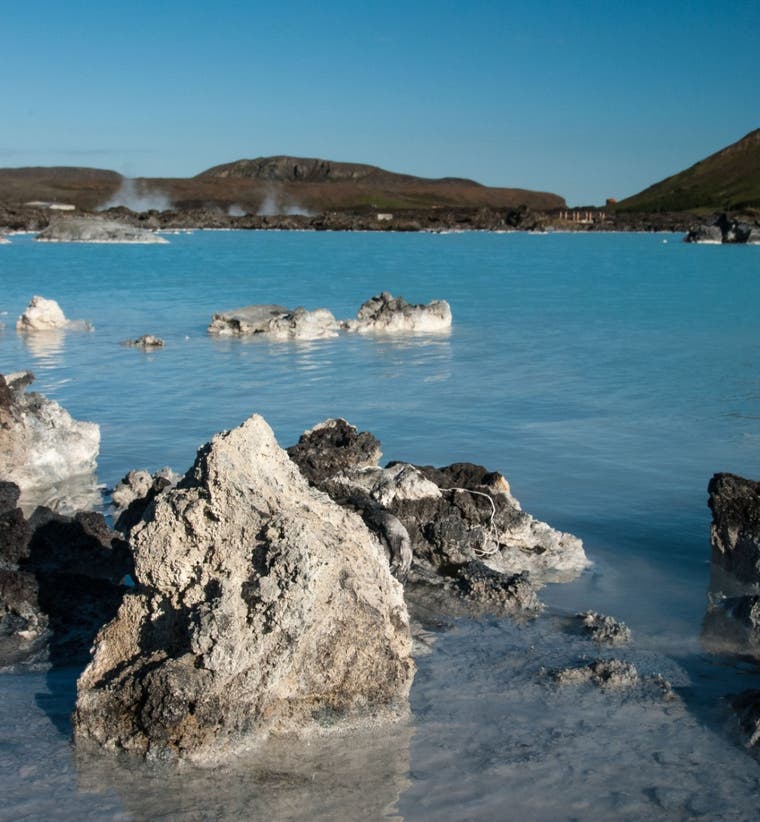 Blue Lagoon geothermal spa in Iceland, showing milky blue water surrounded by black lava rocks and steam rising from the warm po