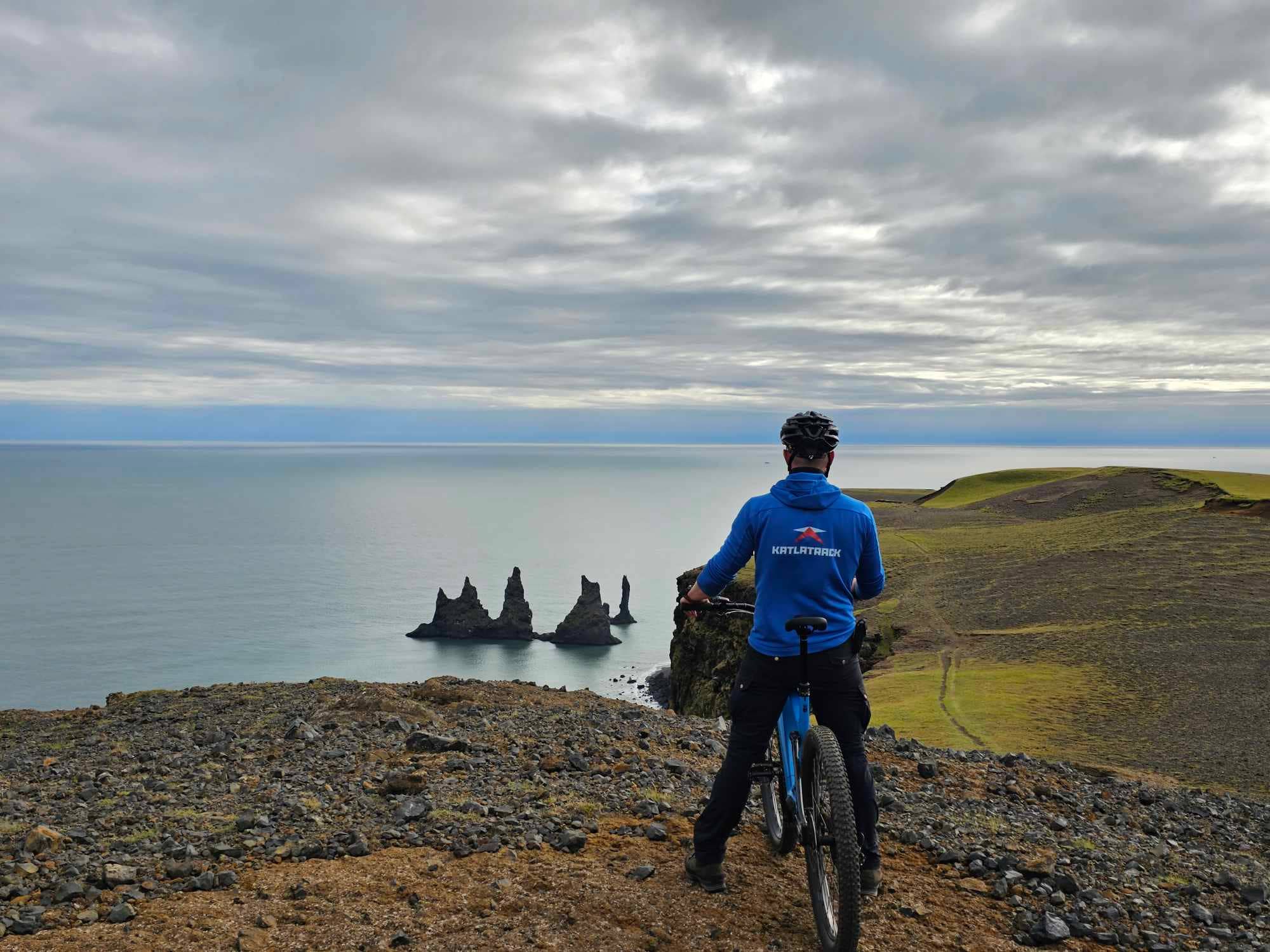 Un ciclista se detiene para disfrutar de las magníficas vistas de los Farallones Marinos de Reynisdrangar y el océano Atlántico desde el pico Reynisfjall.